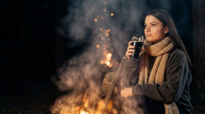 Девушка с гитарой у костра с тёмным пивом