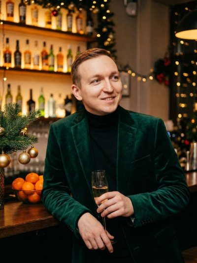 Мужчина в бархатном пиджаке у бара в гирляндах